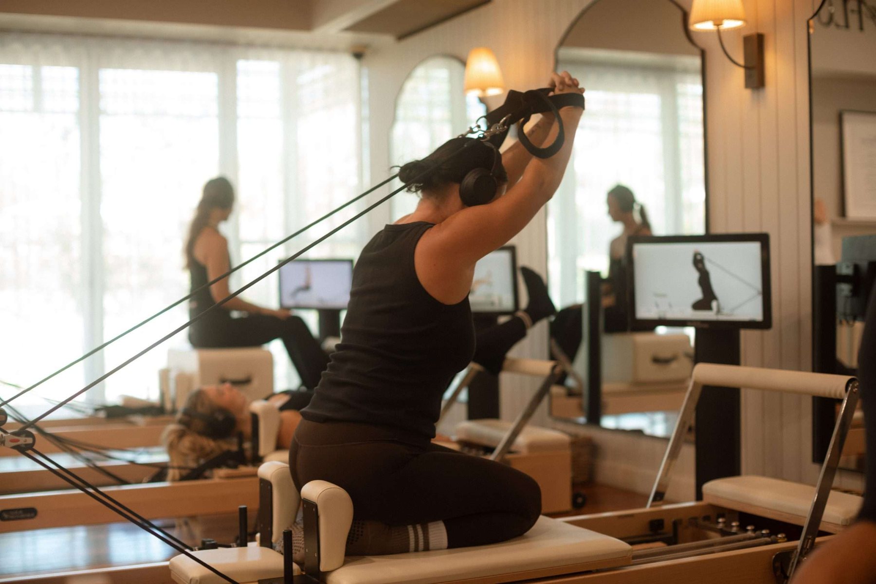 A member wearing wireless headphones during a guided reformer session